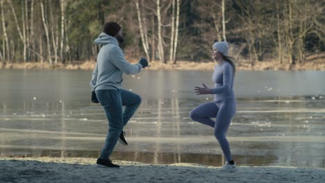 wide shot of adult caucasian couple warming up before winter swimming.