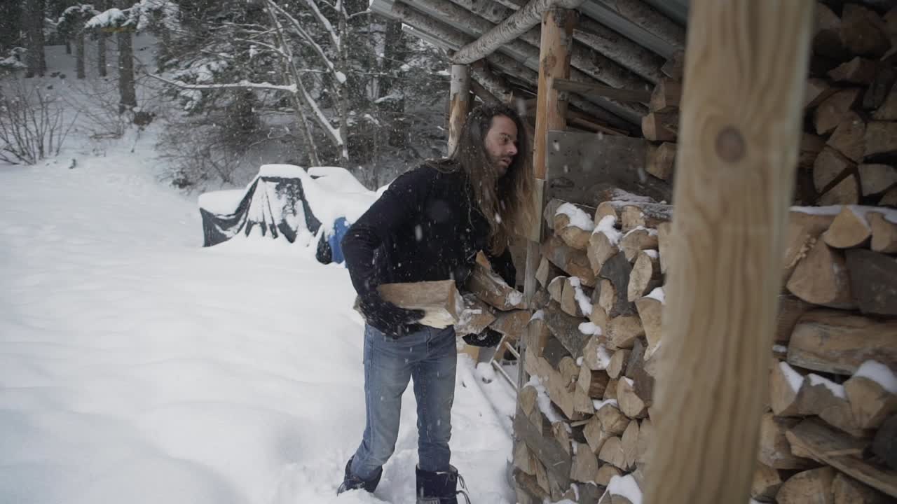 Uomo che prende legna da ardere da una legnaia in inverno.