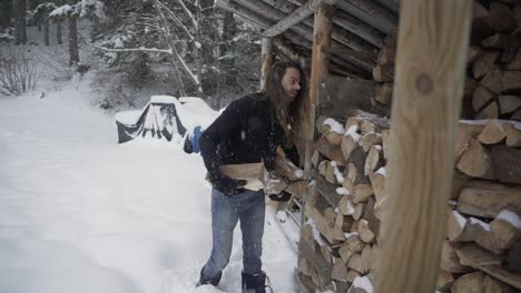 male taking firewood from shed in winter