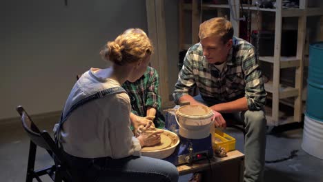 woman teaches little boy to work with pottery wheel