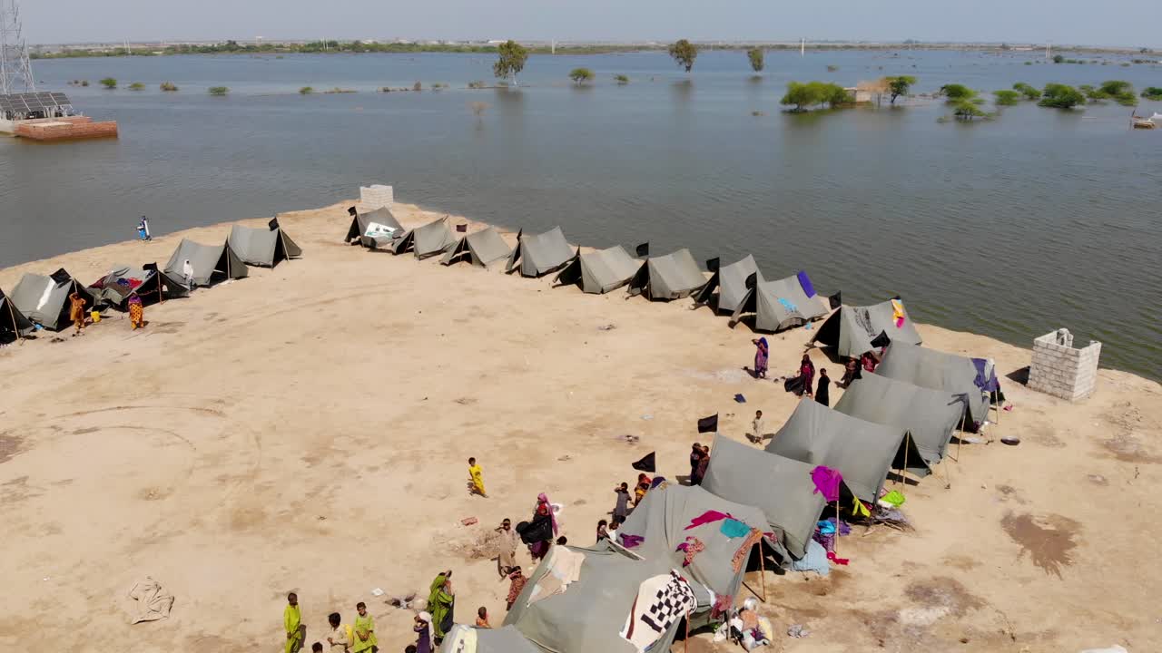 vista aérea del campamento improvisado con tiendas de campaña para albergar a los refugiados de las inundaciones al lado de una carretera elevada rodeada de aguas expansivas en la zona rural de jacobabad, sindh