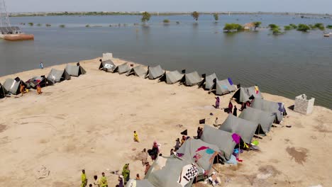 aerial view of makeshift camp with tents to house flood refugees beside only elevated road surrounded by expansive flood waters in rural jacobabad, sindh