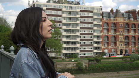 attractive latina woman leaning on the railing of a bridge, thinking and looking around