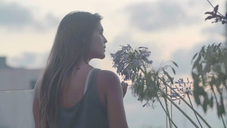 as the sun sets, a young woman takes in the cityscape from a glass railing