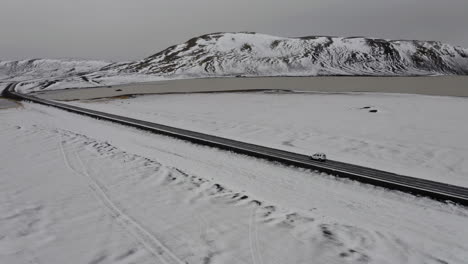 aerial: side follow of car driving on a snowy road in iceland
