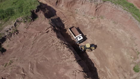 un disparo de drone de un excavador cargando en un camión en un desarrollo de propiedad