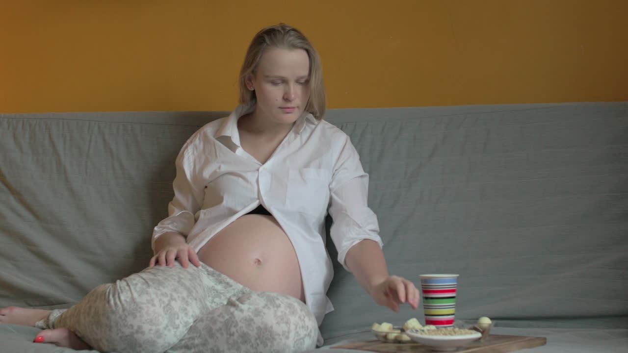 беременная женщина ест и отдыхает дома