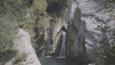disparo de la cascada cerca de bogova albania en un día soleado sin gente y agua clara con rocas y plantas alrededor del tronco