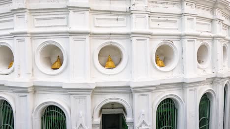 aerial video captures the intricate architecture of wat prayurawongsawas stupa in bangkok, highlighting its white facade and golden statues