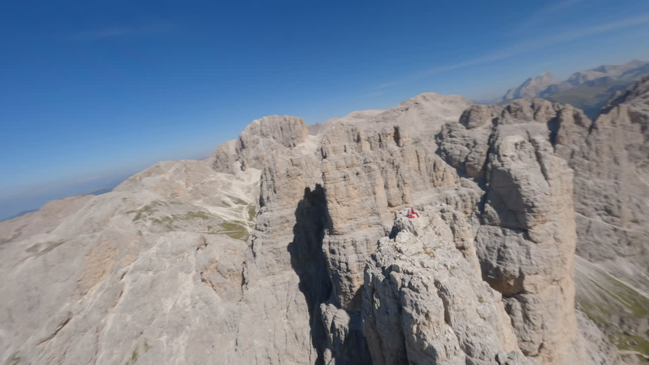personas aventureras sentadas en la cima de un acantilado rocoso en las dolomitas y admiran la vista, el fpv aéreo vuela alrededor