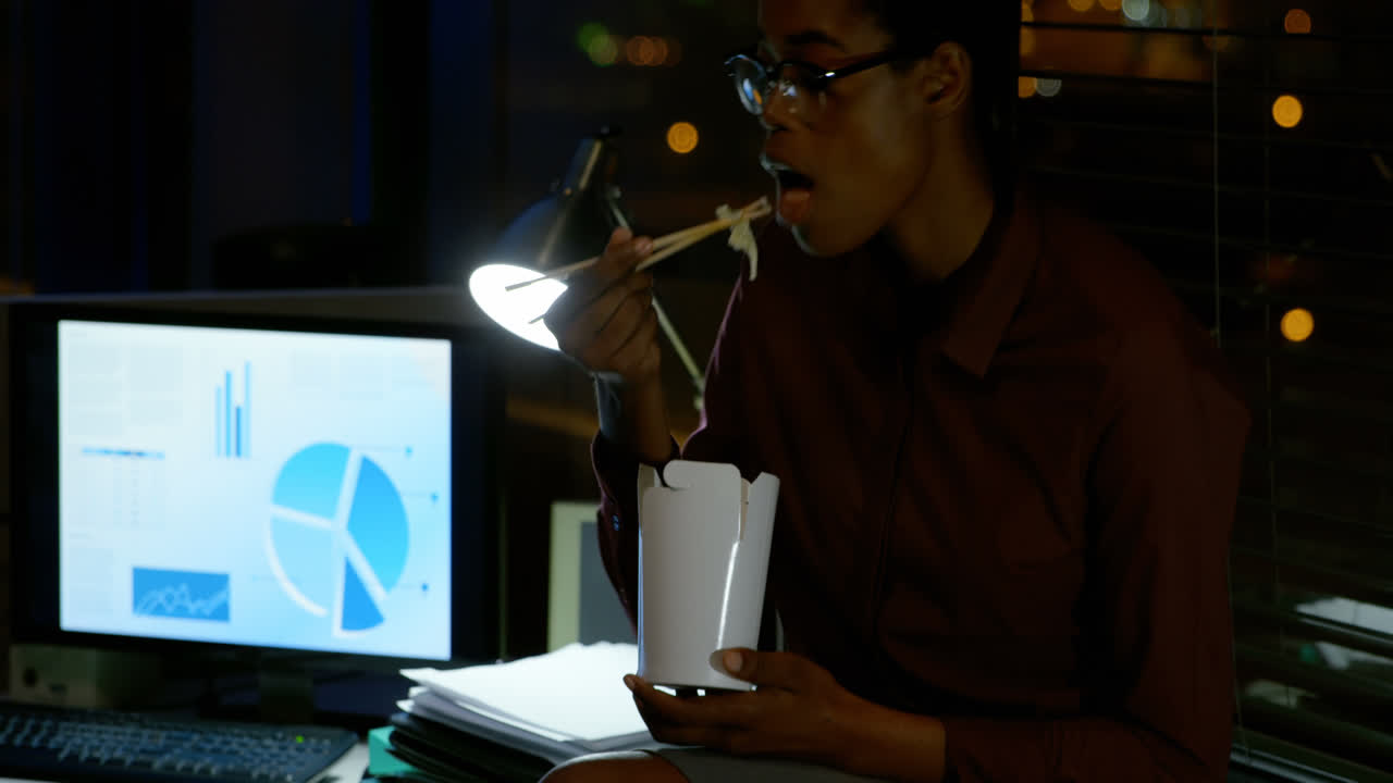 Female executive having noodles at desk 4K