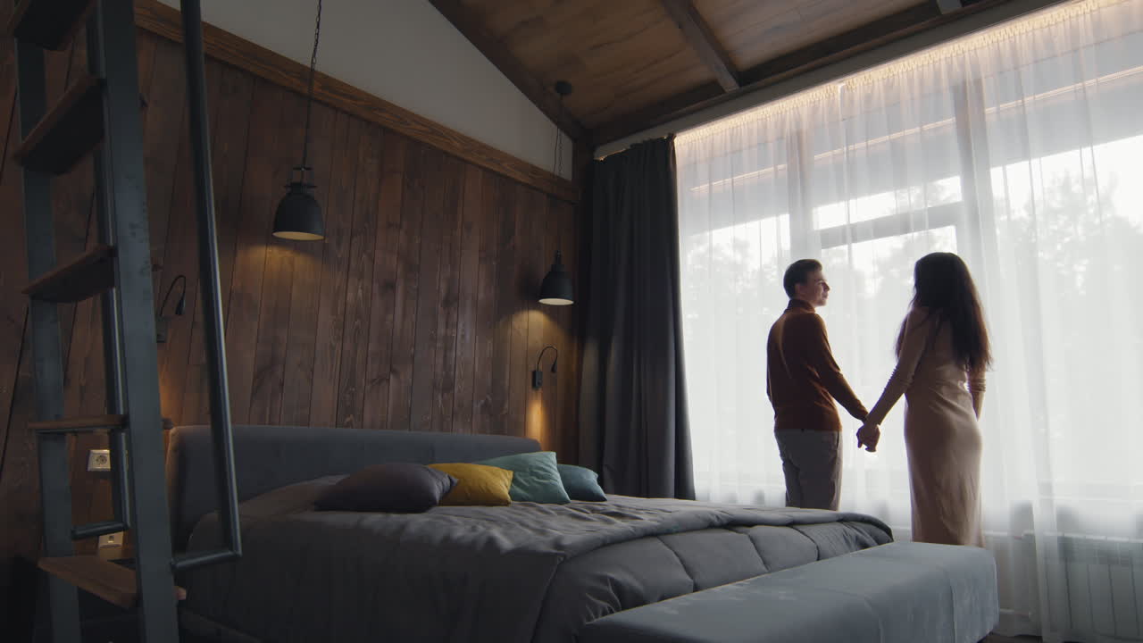 Couple Looking Out the Window of a Cozy Bedroom