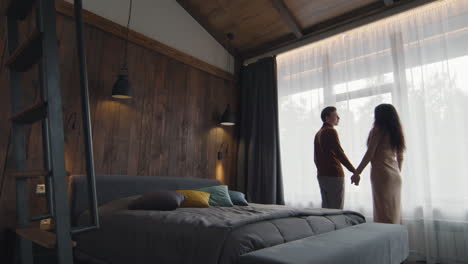 couple looking out the window of a cozy bedroom