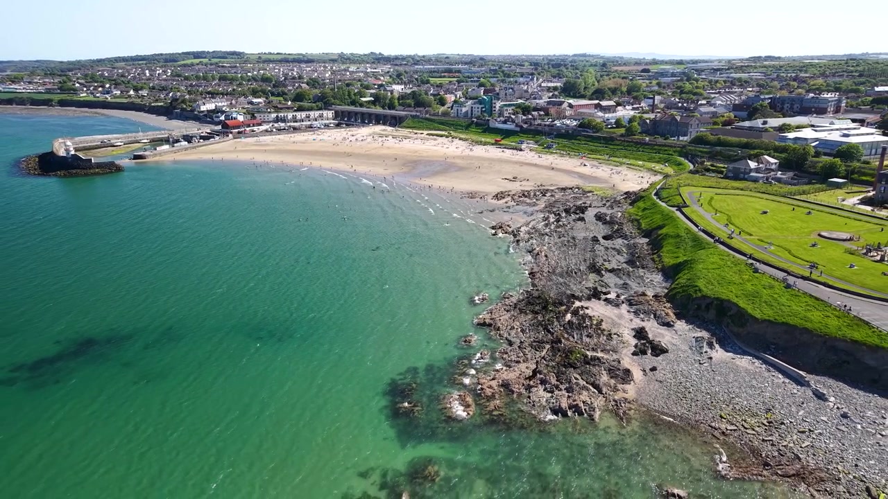 Vacker drönarflygning över Balbriggan Beach fylld med besökare en solig sommareftermiddag