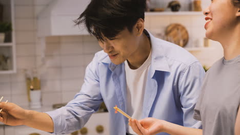 vista de cerca de amigos japoneses sentados alrededor del mostrador de la cocina comiendo comida japonesa