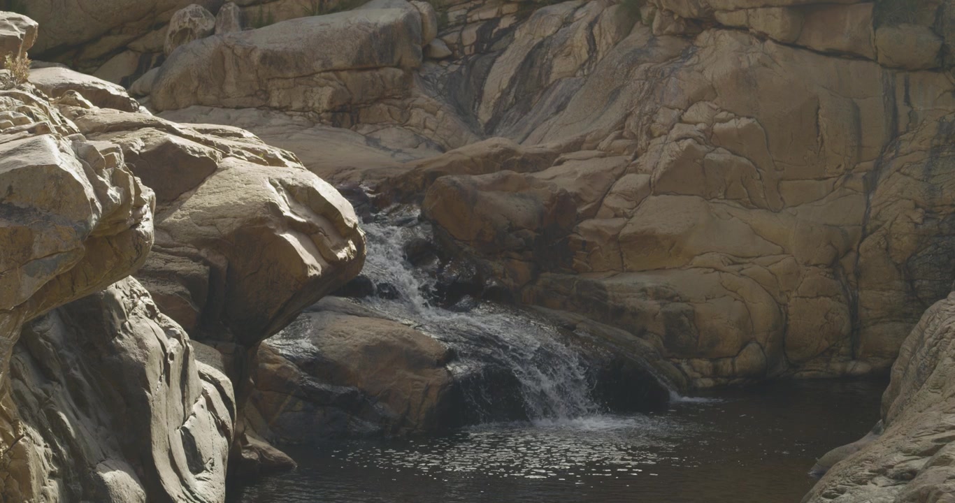 Acqua soleggiata del fiume che schizza sulle rocce in Slow Motion 4K