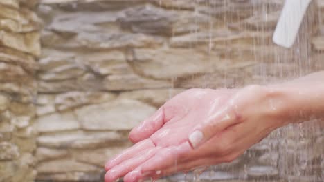 hands of biracial woman relaxing and taking shower in bathroom