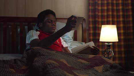 fainting young black man in bed reading before sleeping at night