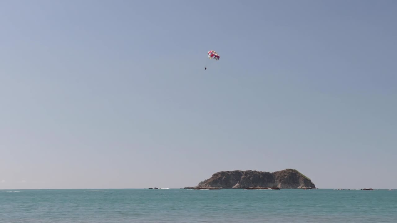 человек практикует парасейлинг над пляжем мануэль антонио, коста-рика