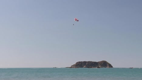 person practicing parasailing over manuel antonio beach, costa rica