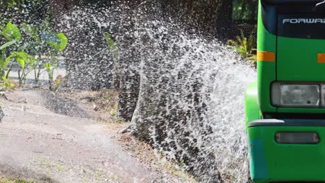 el camión rocia agua sobre la vegetación de la carretera.