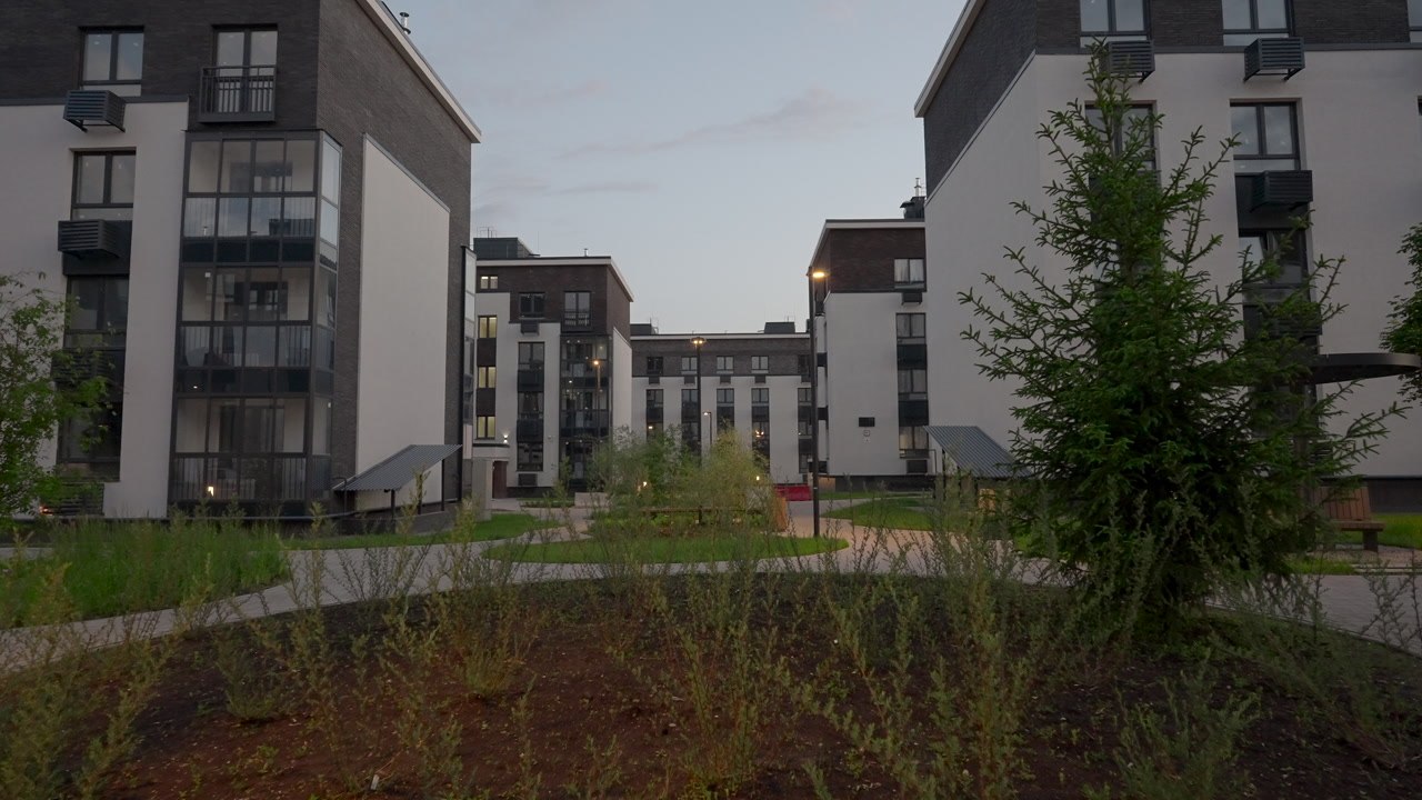 Dusk Residential Courtyard With Central Planting Island Of Young Trees And Wild Shrubs, Curved Paver Pathway