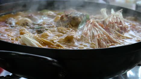 sprudelnde koreanische fisch- und pilzsuppe, die auf dem gasherd kocht