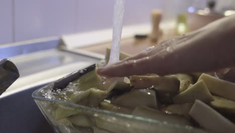 tiro de cerca en cámara lenta como lavar verduras crudas, agua salpicando por encima del fregadero, en la cocina