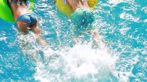 Pareja-Nadando-En-Anillos-Inflables-En-La-Piscina