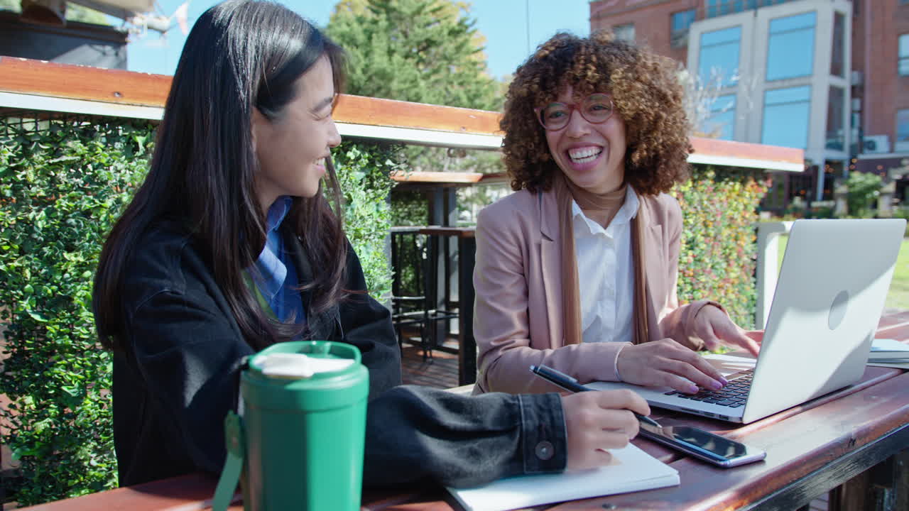 Two Young Businesswomen Working with Laptop Outdoors