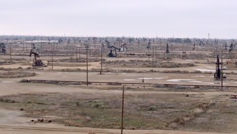 campo de pozos de petróleo con bombas de derrick en el desierto - paso aéreo