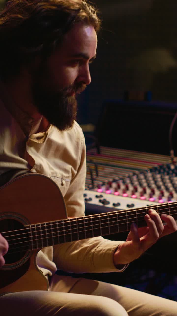 Mand, der spiller akustisk guitar i et musikstudie