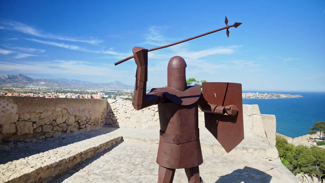 Steel sculpture of a medieval crossbowman on the Santa Barbara Castle parapet, city and mountains on the background