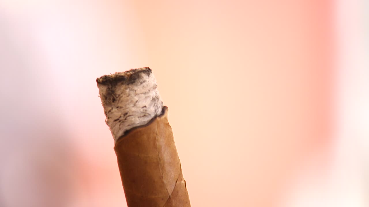 un primerísimo plano de alguien sosteniendo y fumando un cigarro en el caribe