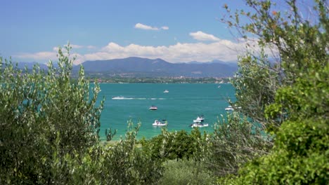 wide establishing shot of boats in the lake with jet ski passing by, on jamaica beach, sirmione, lago garda, lake garda, italy