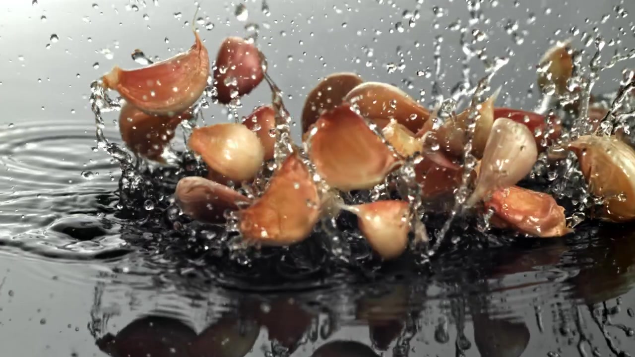 Spicchi d'aglio freschi che schizzano nell'acqua al rallentatore