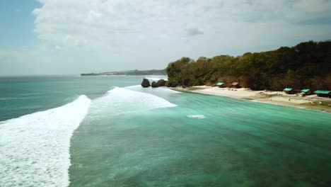 Establecimiento-De-Disparos-De-Drones-Volando-A-Lo-Largo-De-La-Costa-De-La-Playa-De-Padang-Padang-En-Bali,-Indonesia,-Mientras-Las-Olas-Ruedan-Debajo