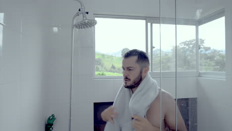 man in the bathroom drying with a towel after shower bearded young guy in a luxury home