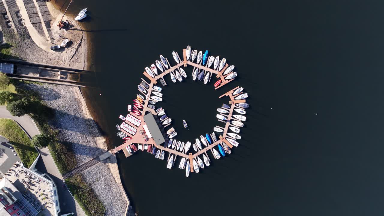 Leisure ships, sailing boats and motor yachts in a circular pattern docked at the harbor. Aerial top down drone video