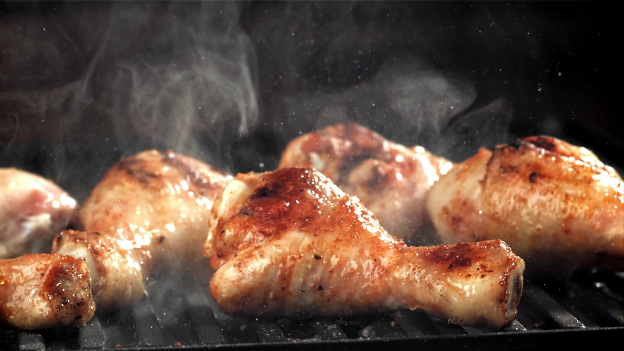 Deliziosi fusi e pezzi di pollo che grigliano sul barbecue