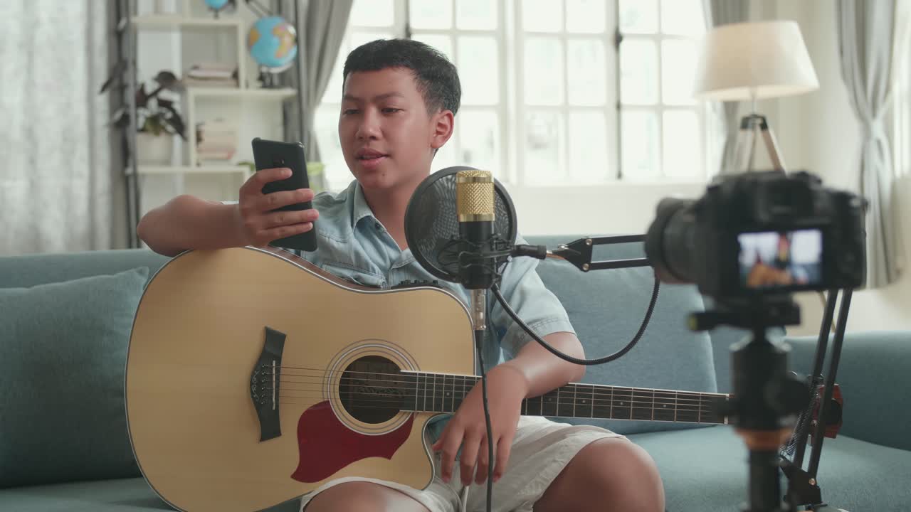 Teenager Playing Guitar and Recording a Video