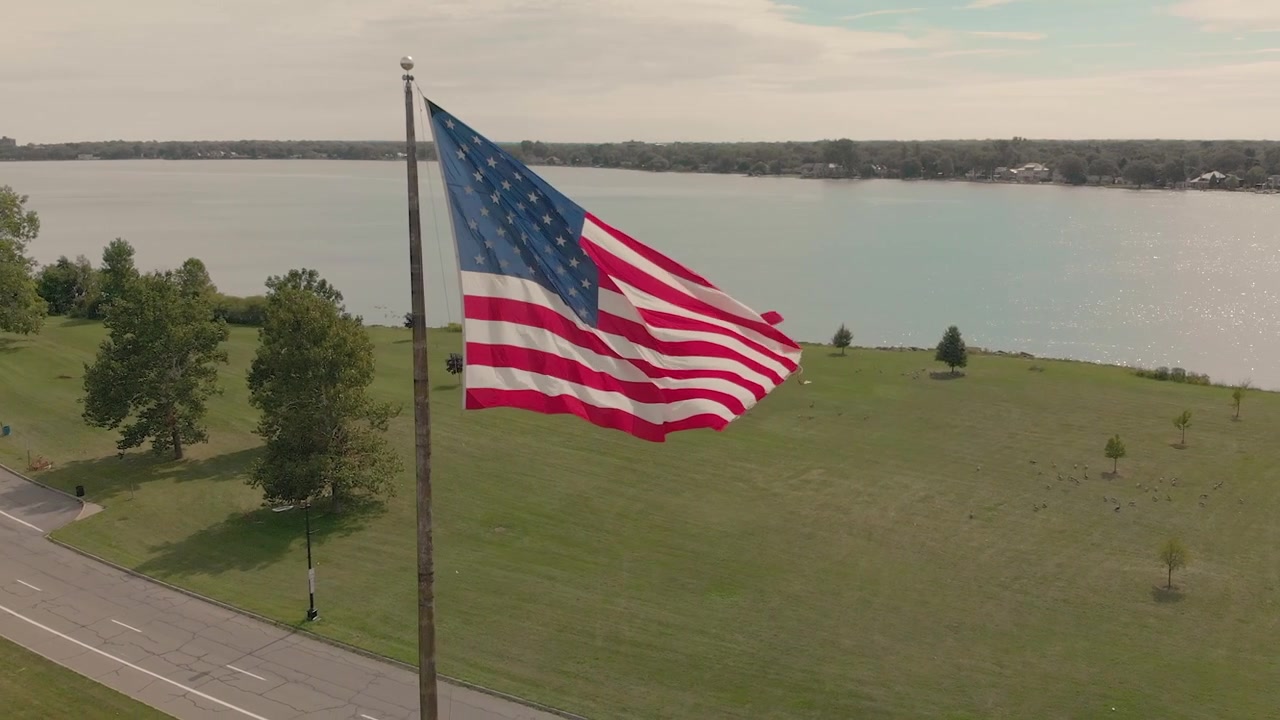 Vista aerea della bandiera americana che sventola in un parco con lago e skyline della città