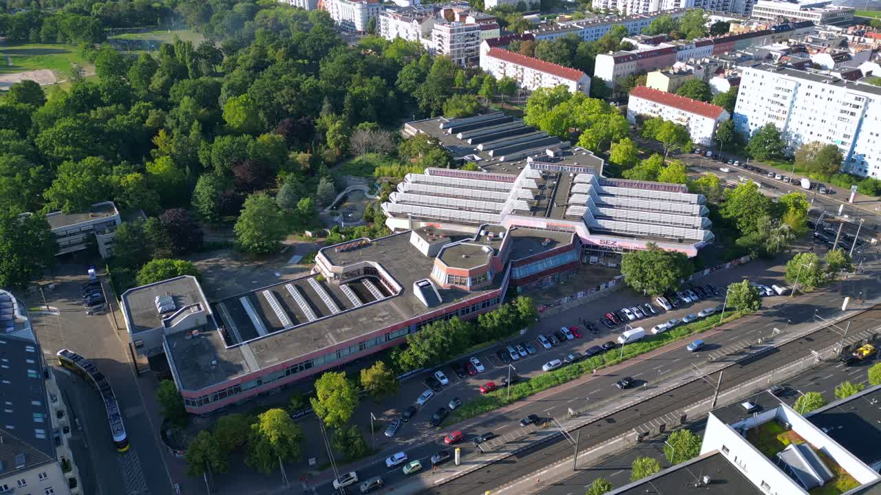 Sez and Volkspark Friedrichshain in Berlin, showcasing its lush greenery, a passing tram on a sunny day. Great aerial view flight drone camera pointing down