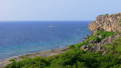 Drone-trucking-pan-around-Caribbean-island-coastline-as-Catamaran-floats-in-water