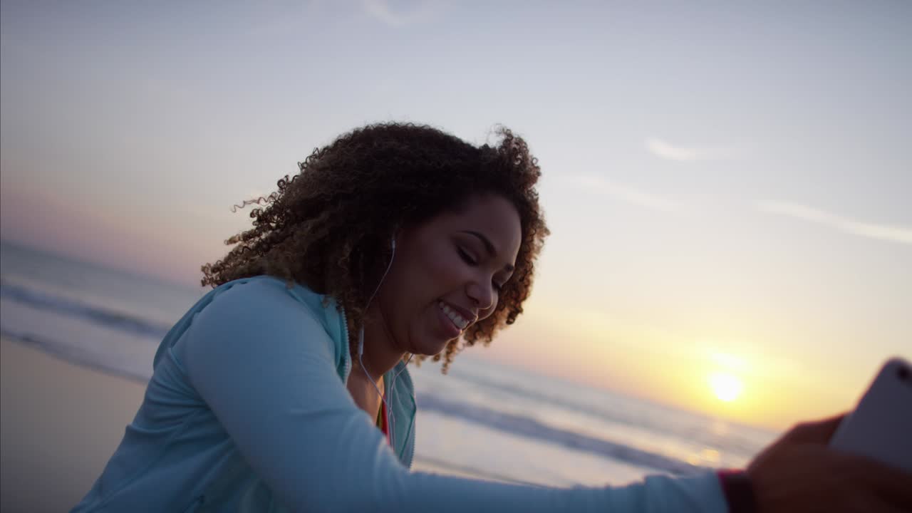 African American female listening to music on beach
