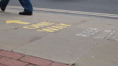 Close-Up-Shot-of-Pedestrians-Feet-Walking-Over-One-Way-Pavement-Marking-In-Oxford-England