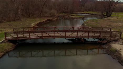 drone view of a footbridge crossing a beautiful twisting river