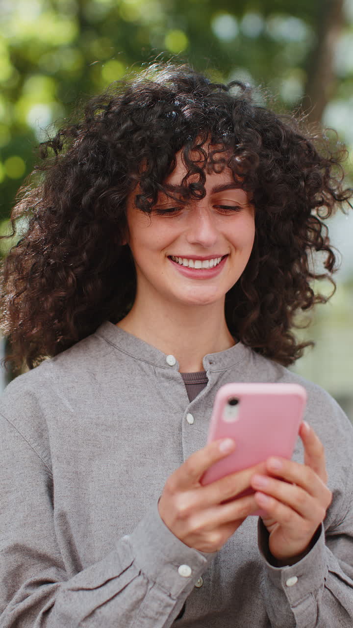 Giovane donna felice che usa lo smartphone per digitare messaggi di testo su un'applicazione di social media online