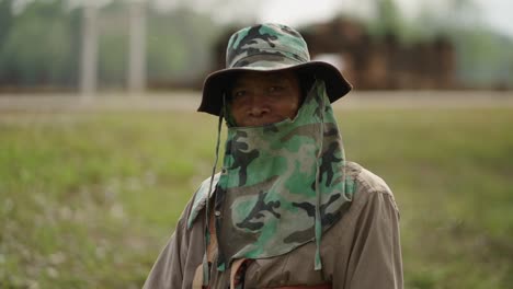 a person wearing a camouflage hat and face covering in a field