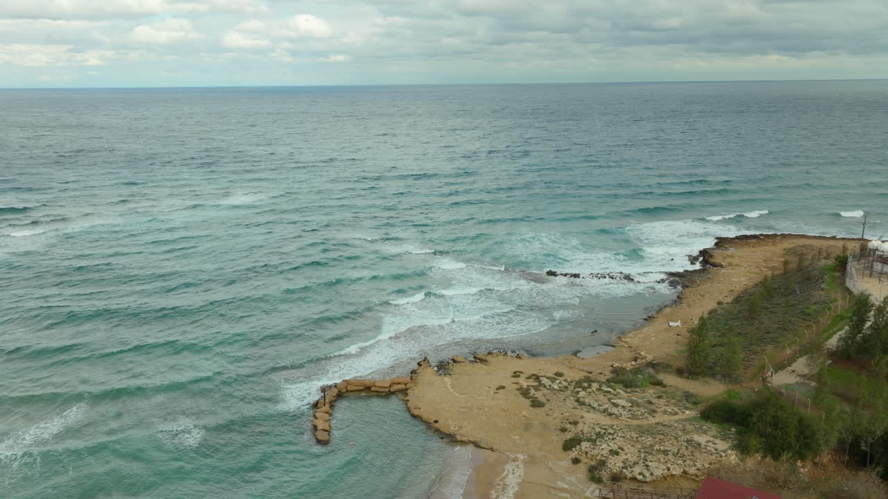 Aerial shot natural allure of the coast near Kapparis, Paralimni, turquoise waves of the Mediterranean gently caress the golden sands and man-made sea defenses